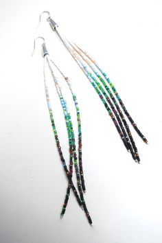 multicolored beads are hanging from the end of a pair of ear wires on a white surface