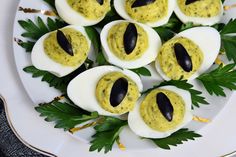 deviled eggs with black olives and parsley on a white plate, ready to be eaten