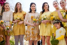 a group of women standing next to each other in dresses and holding flowers on their heads