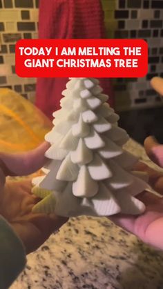 someone is holding a small christmas tree made out of marshmallows and plastic