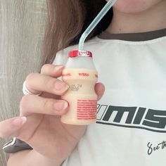 a woman holding a bottle of milk with a straw in her mouth