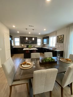 a dining room table with chairs and plates on it in front of an open kitchen