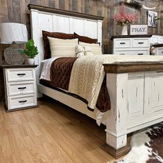 a white bed sitting on top of a wooden floor next to a cowhide rug