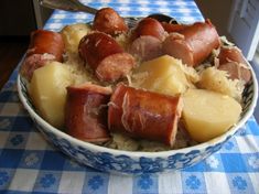 a bowl filled with meat and potatoes on top of a blue checkered table cloth