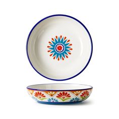 a bowl with an orange and blue flower design on the side, next to a white bowl