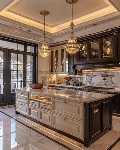 a large kitchen with marble counter tops and black cabinetry, along with chandeliers hanging from the ceiling