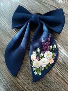 a blue bow with flowers on it sitting on top of a wooden table next to scissors