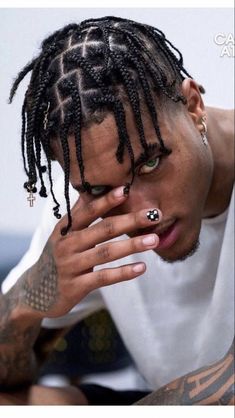 a man with dreadlocks and tattoos on his face is looking at the camera