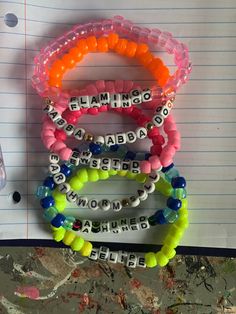 several bracelets with words written on them sitting on top of a piece of paper