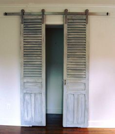 an open door with wooden slats on the inside and outside, in front of a white wall