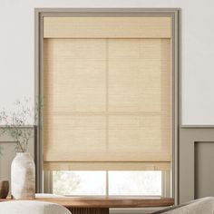 a living room scene with focus on the blinds and table in front of the window