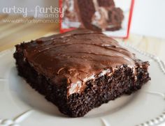 a piece of chocolate cake sitting on top of a white plate next to a box of brownies