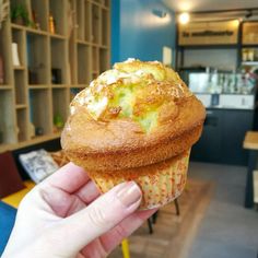 a person holding up a muffin in a room with blue walls and wooden shelves