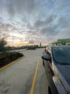 a car parked in a parking lot next to a gas station with the sun going down