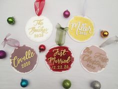 six personalized christmas ornament hanging on a table with ornaments around them and the names of each member