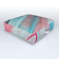 a blue, pink and white pillow on a white surface