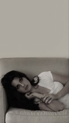 a black and white photo of a woman laying on a couch