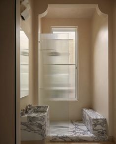 a bathroom with two sinks and a shower in the corner, along with marble steps leading up to an open window