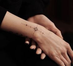 two hands holding each other with small stars on their wrist and one has a star tattoo on it