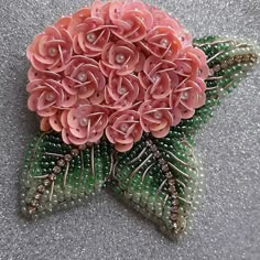 a star shaped brooch with pink flowers and green leaves on it's side