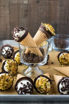 chocolate covered ice cream cones in a glass bowl on top of a metal tray with other desserts