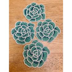 three green and white succulents sitting on top of a wooden table