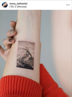 a woman's arm with a mountain tattoo on it