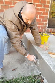 a man in a brown jacket is working on the side of a building with tools