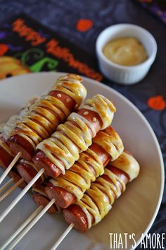 several skewered hotdogs are on a plate with toothpicks and dipping sauce