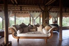 a living room filled with lots of furniture and pillows on top of wooden flooring