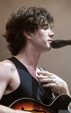 a man holding a guitar and singing into a microphone