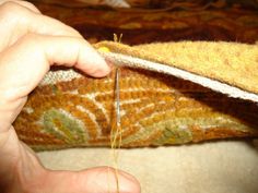 a person is sewing on a piece of fabric with needle and thread in their hands