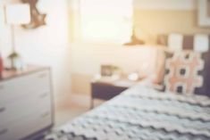 blurry image of a bedroom with bed, dresser and television in the background at sunset