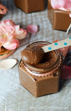 a jar filled with chocolate frosting and a wooden spoon sitting on top of it