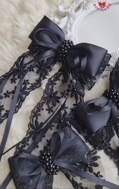 black lace garters with bows and pearls on white furnishing next to mirror