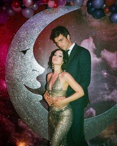 a man and woman standing next to each other in front of a moon with stars