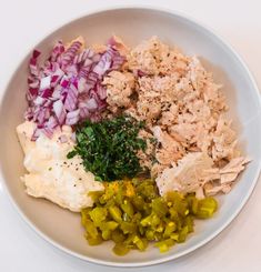 a white plate topped with meat, onions and green peppers next to an egg mixture