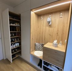 an empty room with shoes and other items on shelves in the corner, along with a wall mounted coat rack