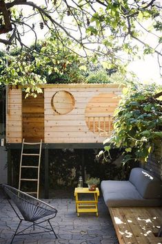 an outdoor living area with a couch, table and ladder in the middle of it