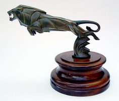 a bronze statue of a leaping panther on a wooden base with a white background in the foreground