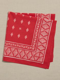 two red napkins with white designs on them sitting next to each other in front of a beige background