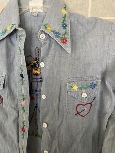 a denim shirt with embroidered flowers and hearts on it