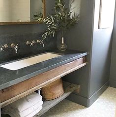 a bathroom sink sitting under a mirror next to a wooden shelf with towels on it