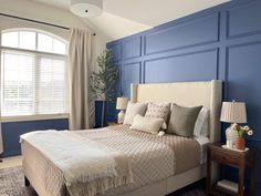 a bedroom with blue walls and white bedding