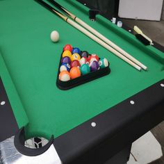 a pool table with billiards, cues and ball resting on the top surface