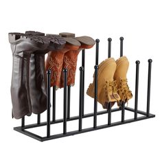 four pairs of boots are hanging on a black metal rack with five poles and one pair is brown