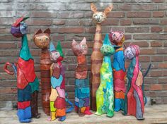 several colorfully painted cats and giraffes sitting on a shelf in front of a brick wall