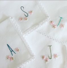 embroidered letters and numbers on white linens with pink flowers in the center, placed next to each other