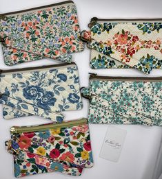 four flowered purses lined up next to each other on top of a white surface