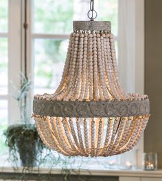 a chandelier hanging from the ceiling in a room with a potted plant